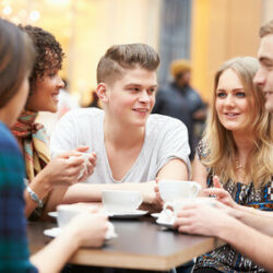 A group of young people sitting around a cafe table with coffees