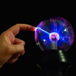 One finger touching a plasma globe ball with blue lightening. 