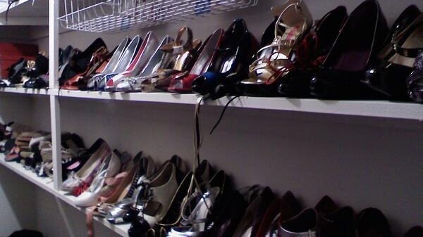 A row of high healed shoes on a shoe rack in a closet