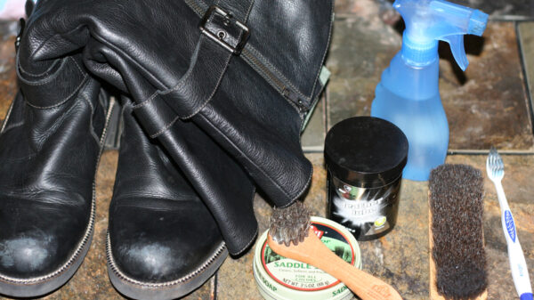 Boots, saddle soap, squirt bottle with water, brushes, and leather lube laid out