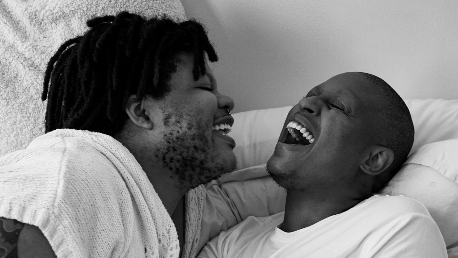 A couple in bed laughing together