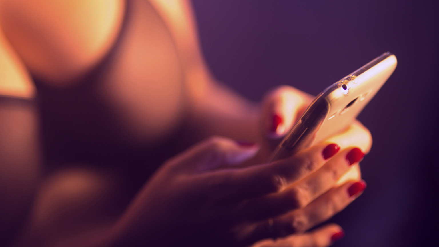 Photo of a feminine person in lingerie with red nails texting