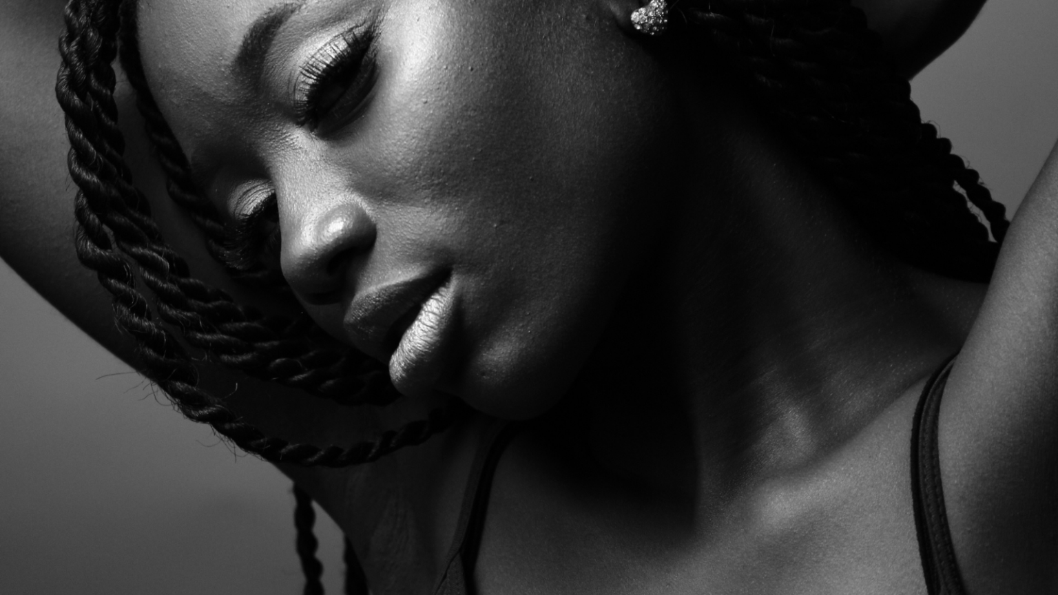 A closeup on the face of a feminine person with dark brown skin with a soft facial expression
