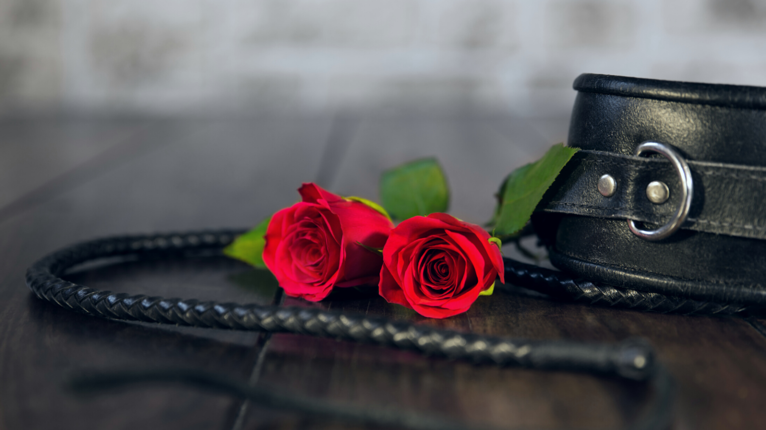 A whip, handcuffs, and two red roses