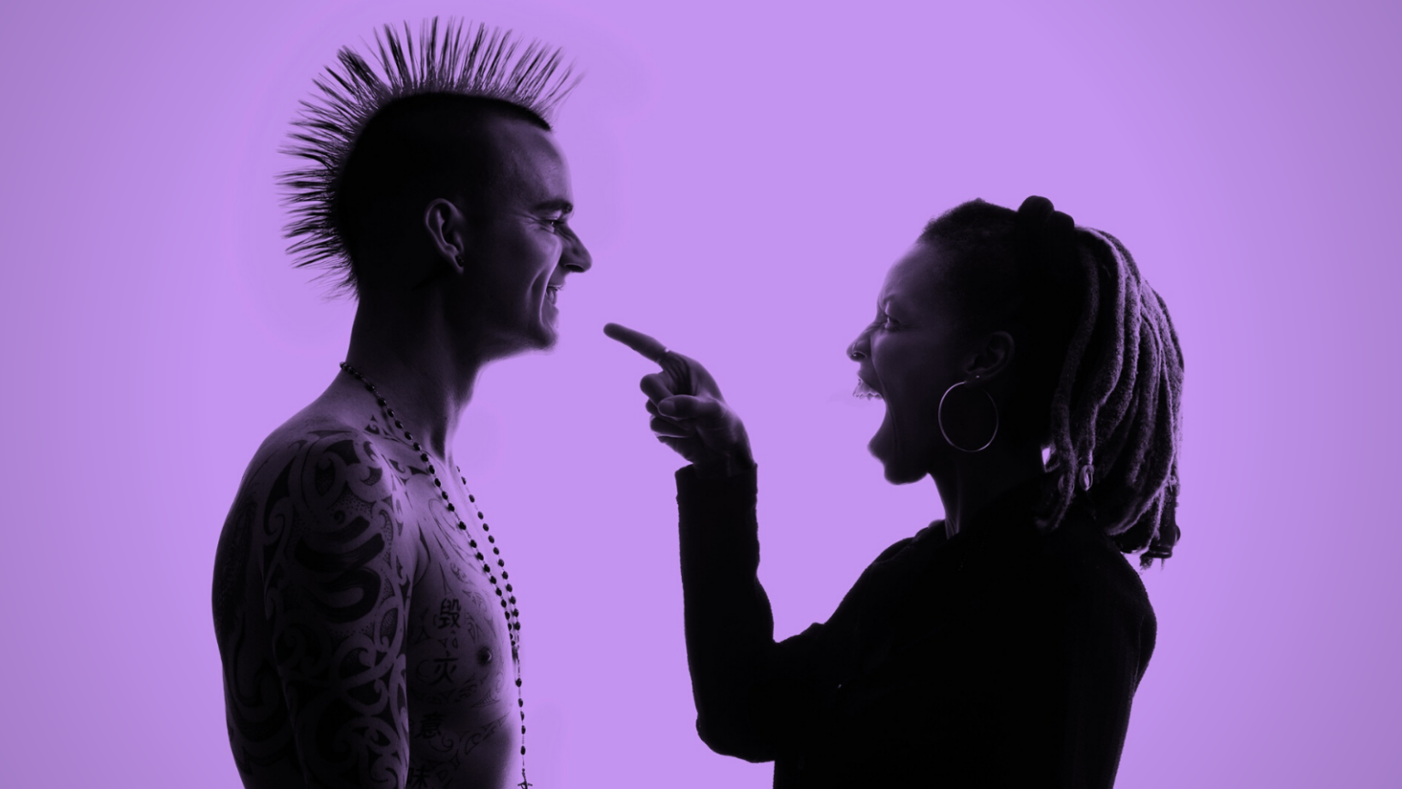 Black woman points and laughs at white man with spiked hair, who is smiling back at her