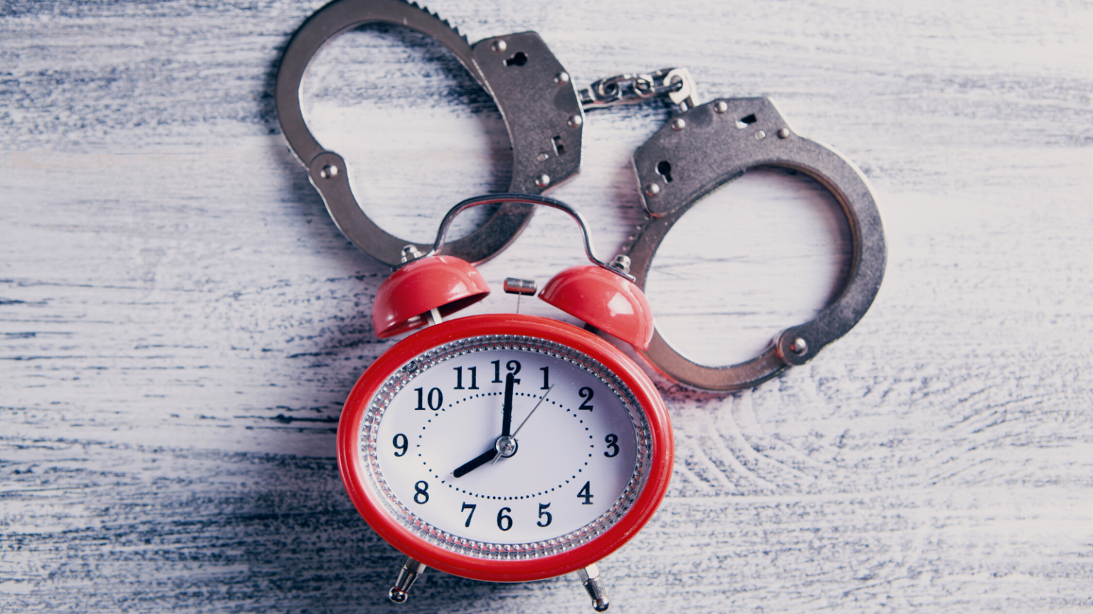 Alarm clock with handcuffs on table.